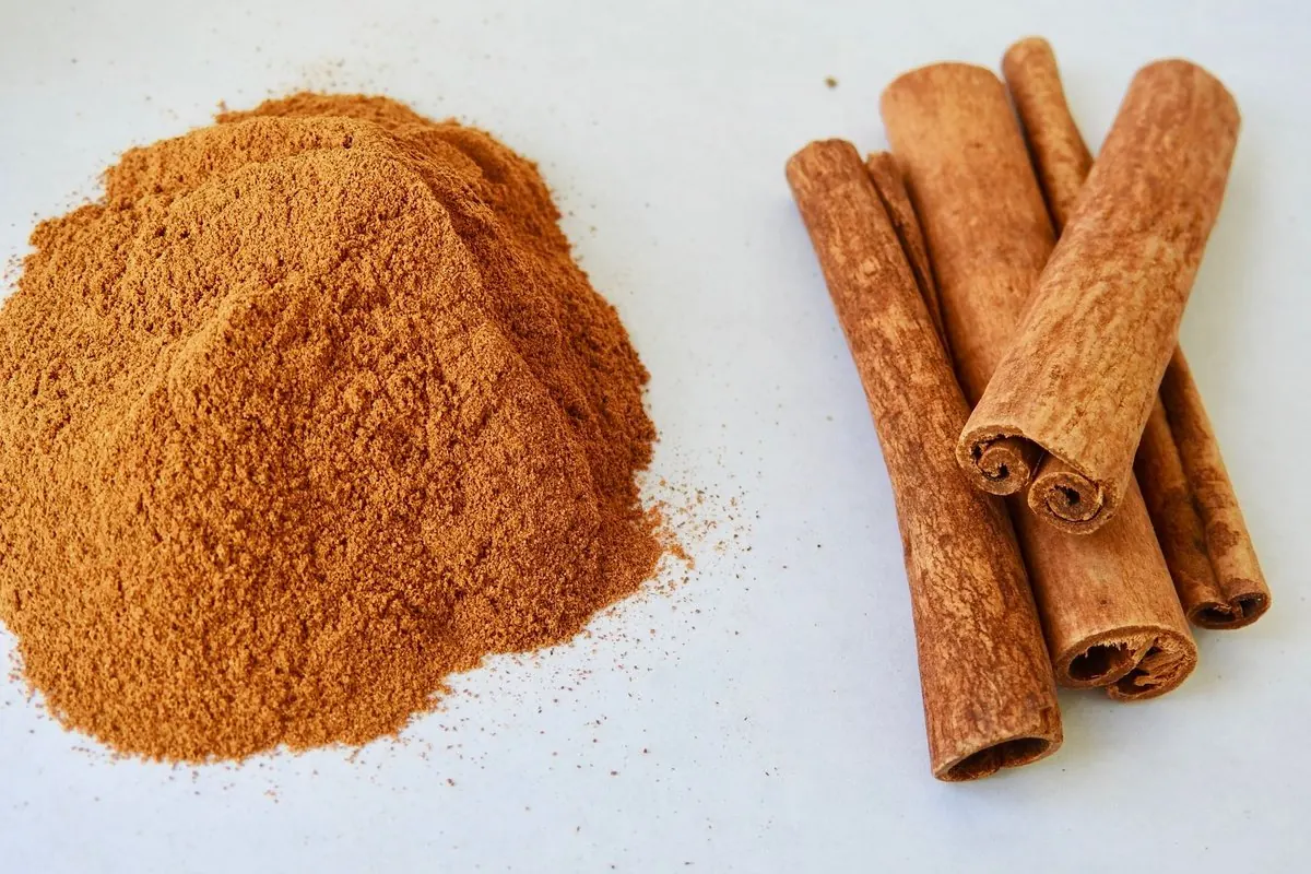 Quế thanh cuộn và đống bột quế trên mặt bàn trắng