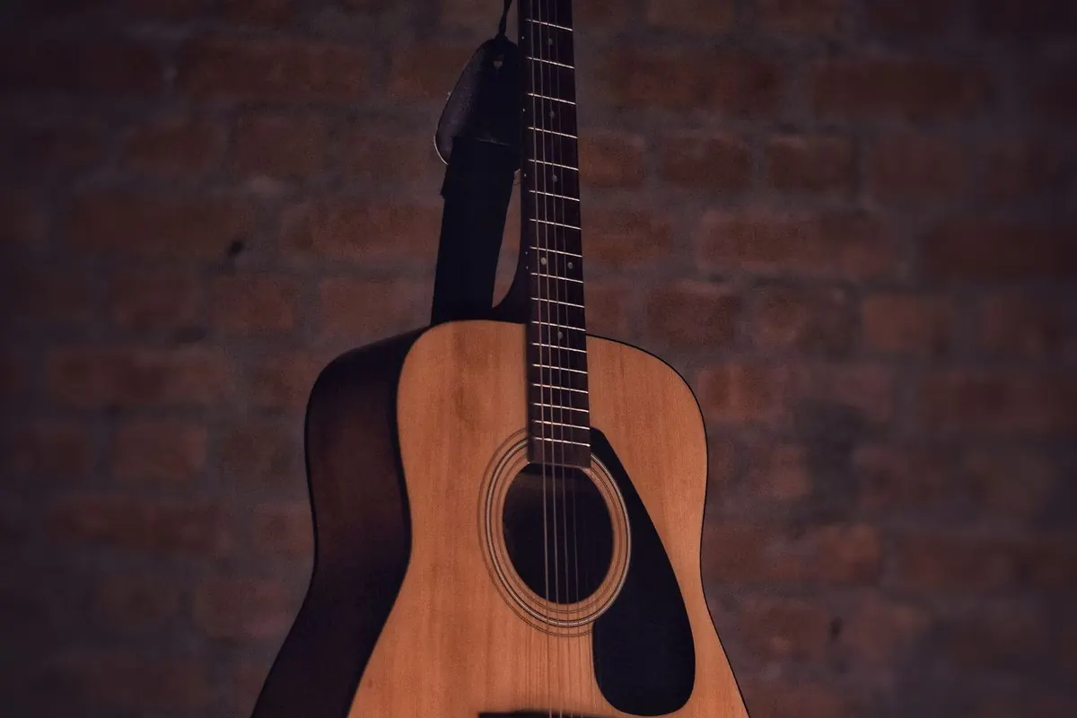 Cây đàn guitar gỗ dựa vào tường gạch nâu
