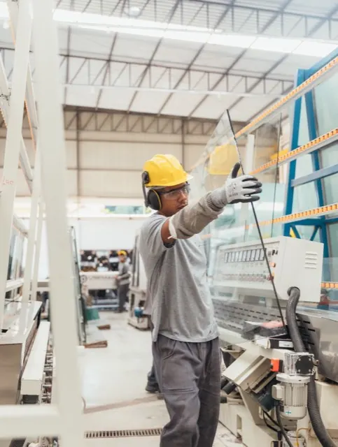 Công nhân đội mũ bảo hộ nâng tấm kính trong xưởng