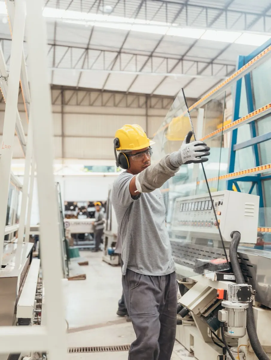 Công nhân đội mũ bảo hộ nâng tấm kính trong xưởng