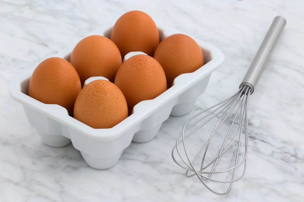 Sáu quả trứng nâu trong khay trắng trên mặt đá