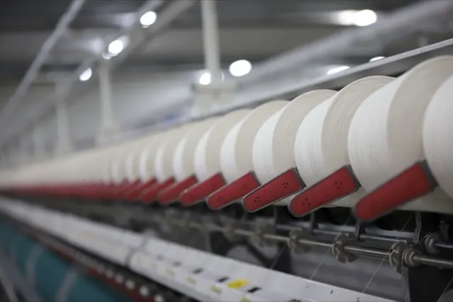 Dàn máy kéo sợi với hàng ống sợi trắng trong nhà máy